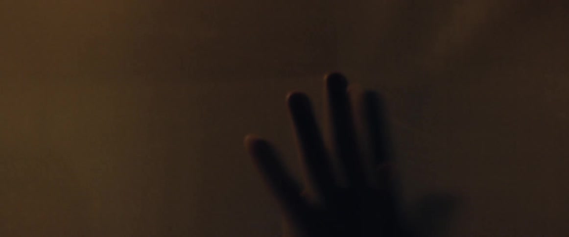 A man raises and lowers his hand against a screen