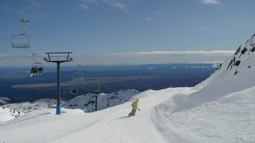 A man is snowboarding down a hill
