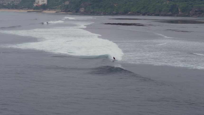 A person rides a wave on his surfboard