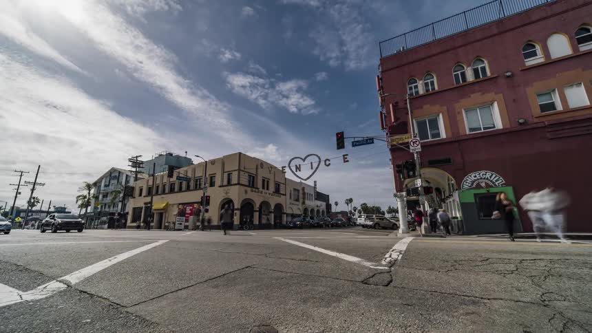The busy intersection has many cars, and people traveling