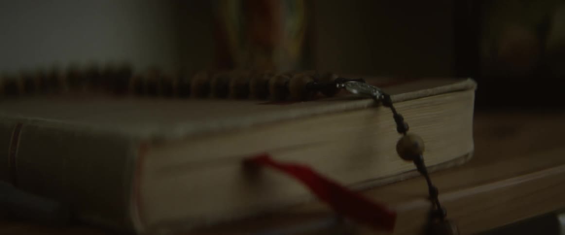 A ribbon is marking a place in a book on shelf inside a room