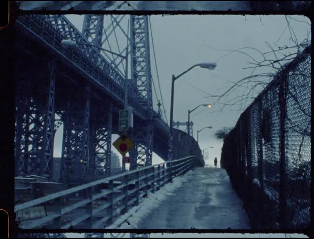Woman walks down a trail in between a bridge and a fence