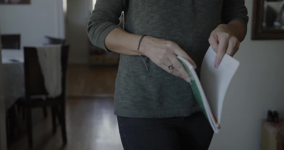 Woman is walking in her home holding notebook