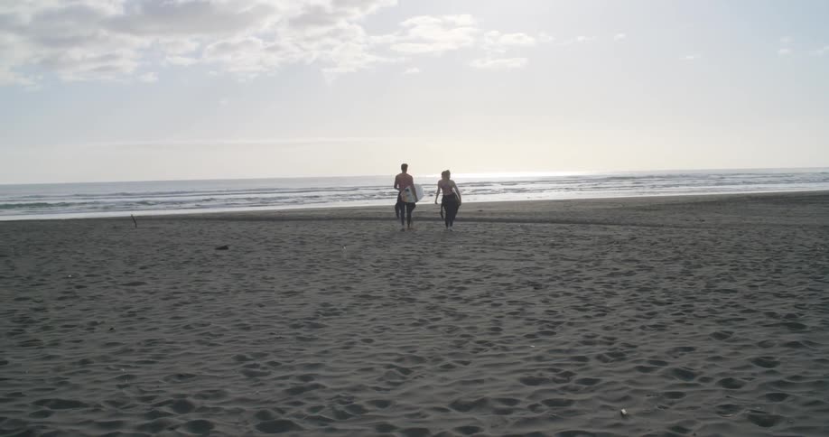 Two people walking on the beach towards the water