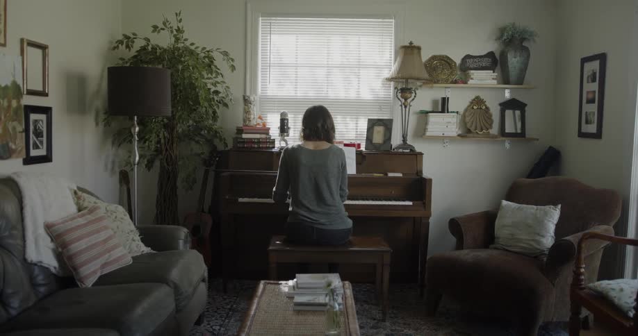 Woman plays piano in a living room