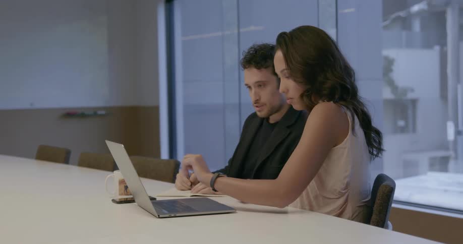A man and woman talk while looking at a laptop