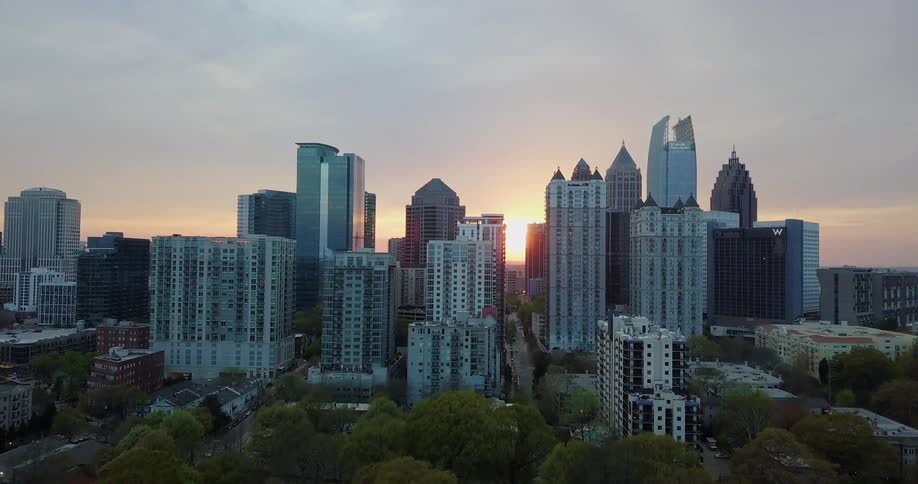 The sun is rising beyond skyscrapers in a city