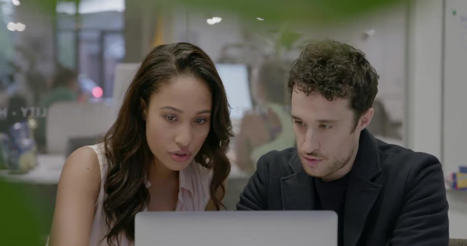 Two coworkers look at a laptop