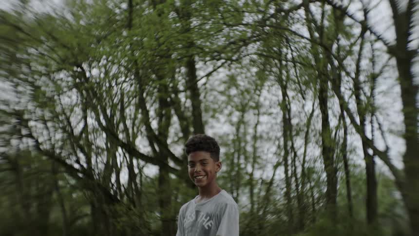 A boy is standing in a natural setting and smiling