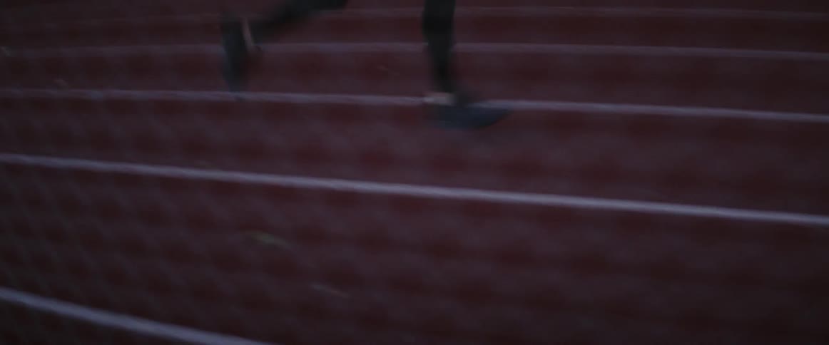 A man is running on a race track at dusk