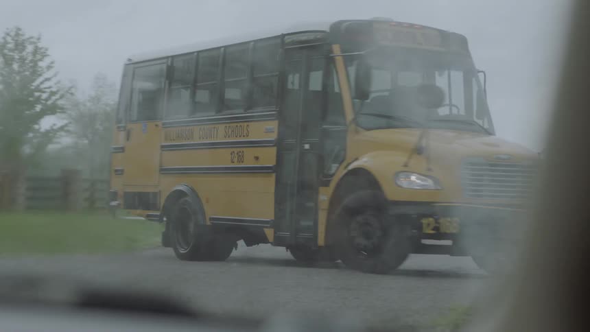 A school bus stopping on a rainy day