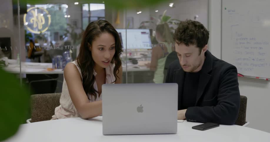 A man and woman sit at a table with a laptop