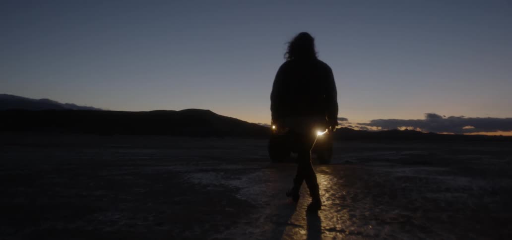 Person walks towards headlights of a jeep at night