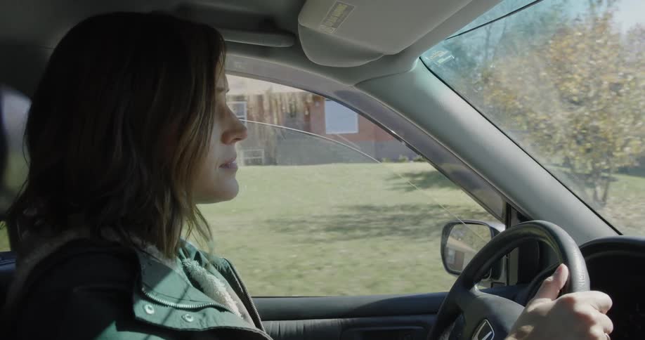 A woman is driving the car in the town