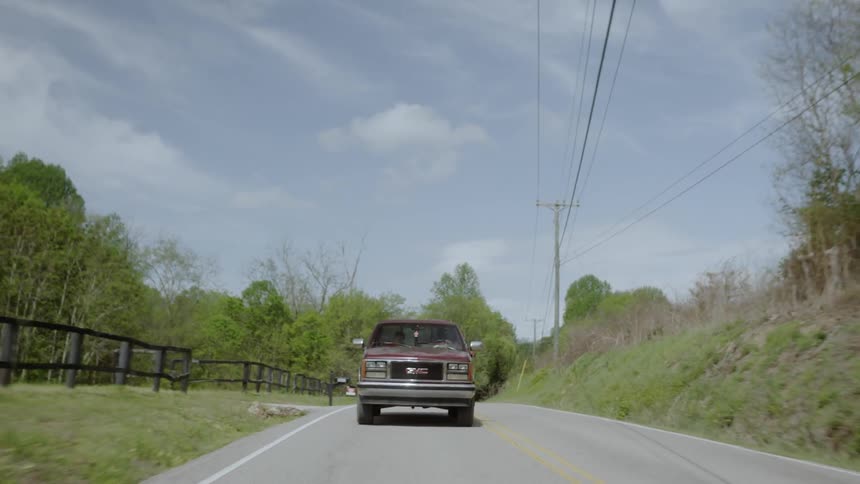 The truck drives down the road on a cloudy day