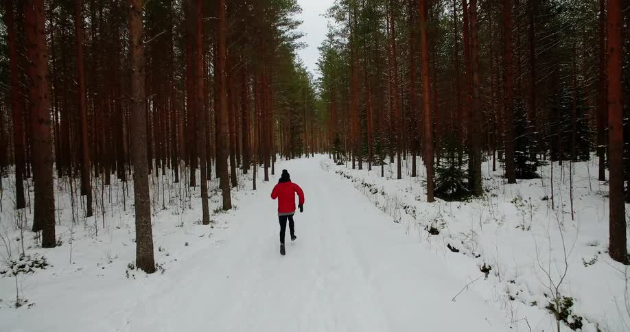 A person runs down the snow filled trail