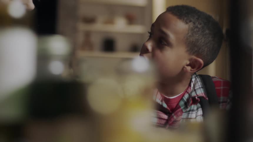 A boy smiles as he talks to an adult