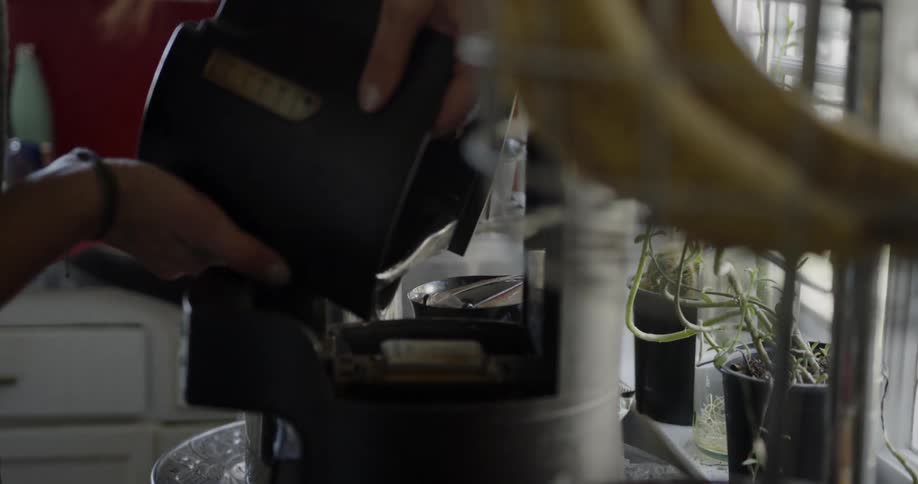Woman pours water into coffee maker in kitchen