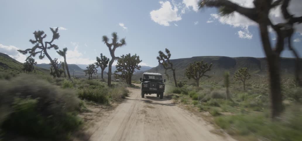 A truck travels on a dirt road through a desert