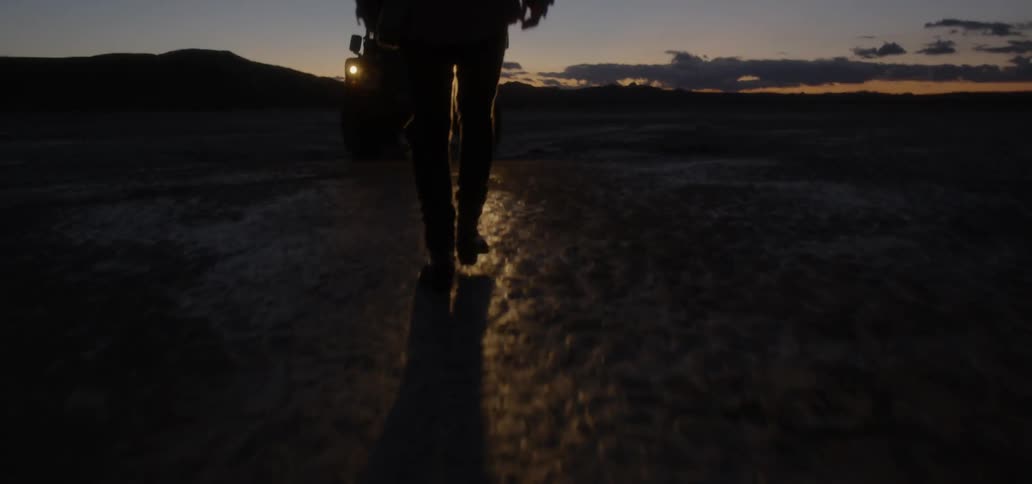 Man walking towards a vehicle in the wilderness at sunset