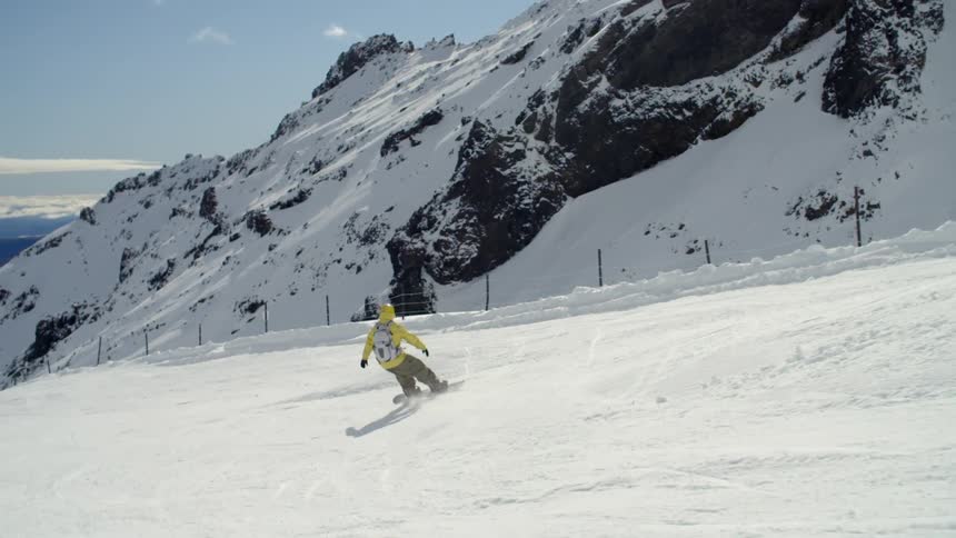 A man is snowboarding down a hill