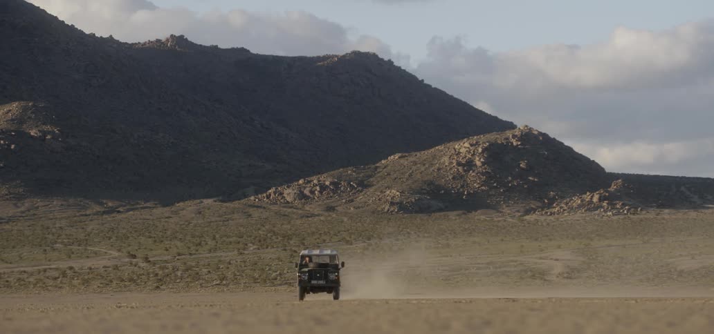 A truck is driving over the long field