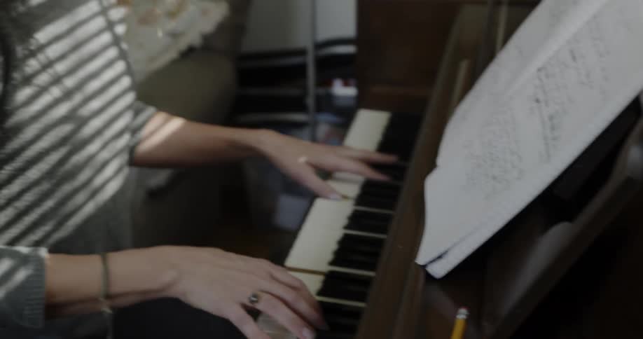 A woman sits by the piano playing the keys