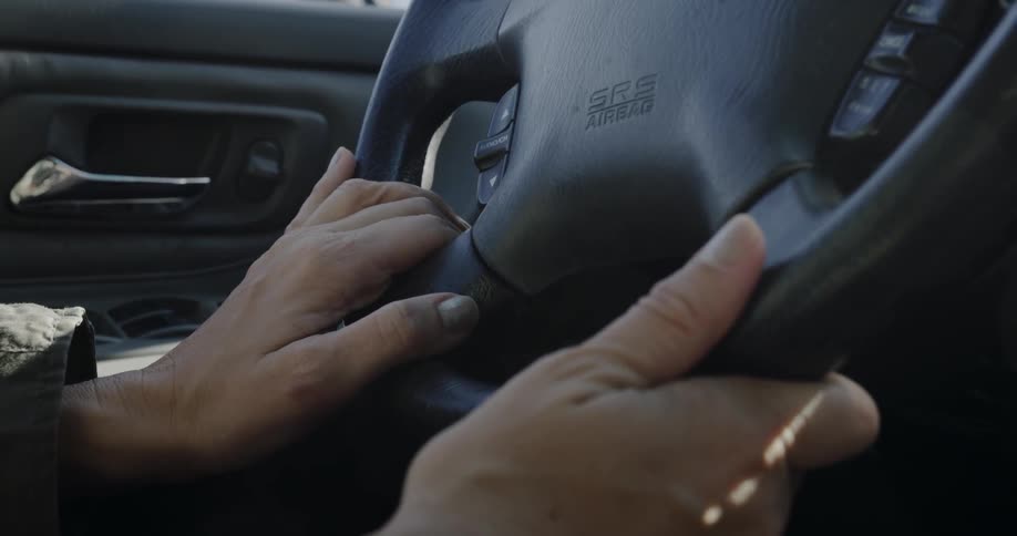 A person is steering a vehicle on a sunny day