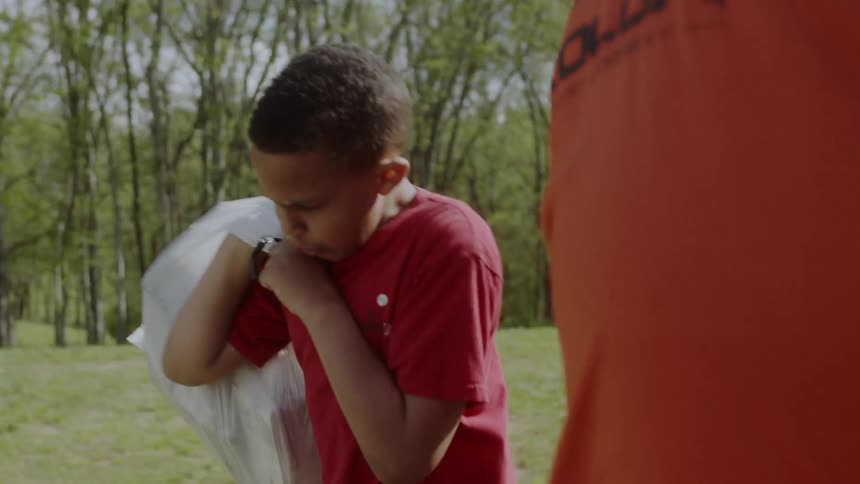 A boy loads a trash bag into the back of a truck