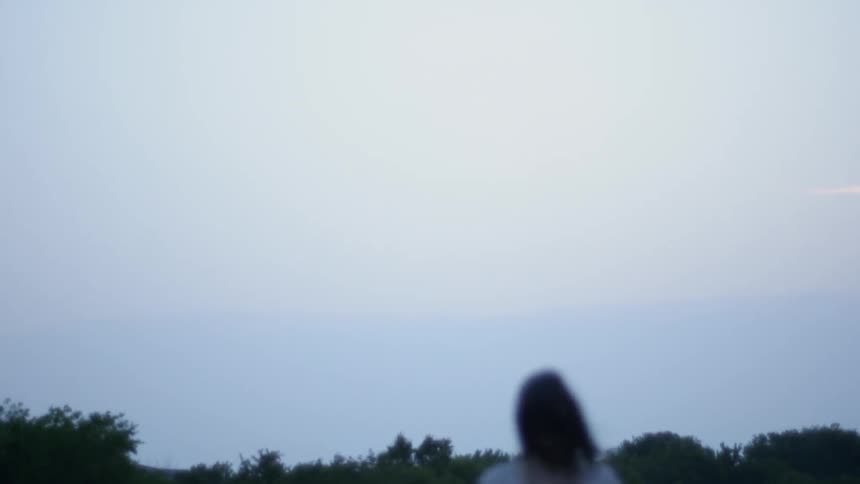 Woman stands in rural field on windy day
