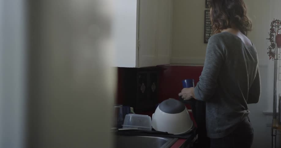 A woman is doing dishes in the kitchen