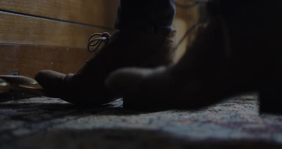 A person wearing boots presses the pedals on a piano