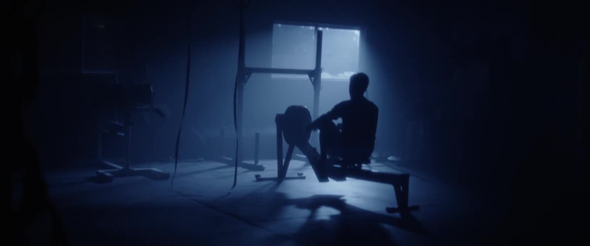 Man uses an exercise machine in a dark room