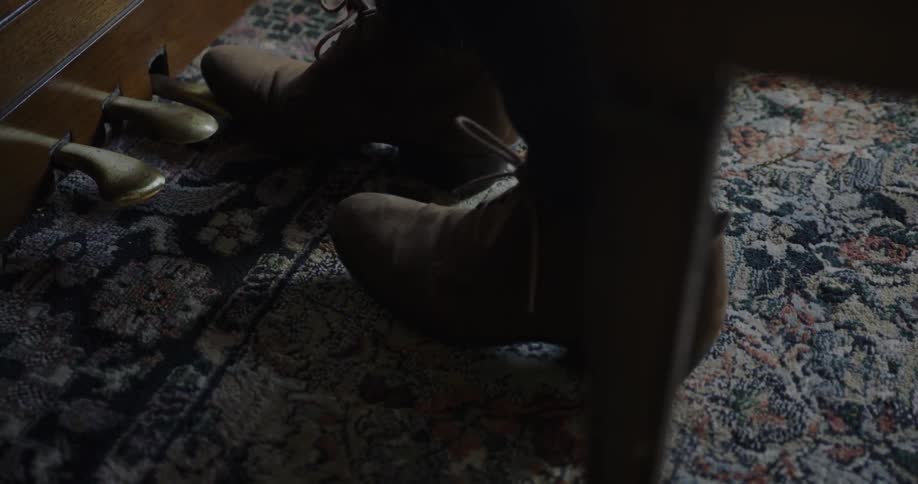 A person taps their feet by a piano