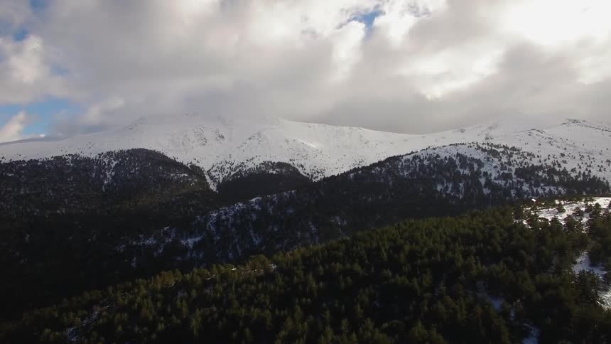 Past the forest covered hills is a snow covered mountain