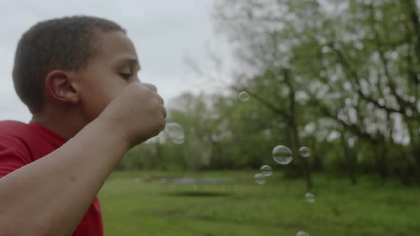 A boy is blowing bubbles in the park