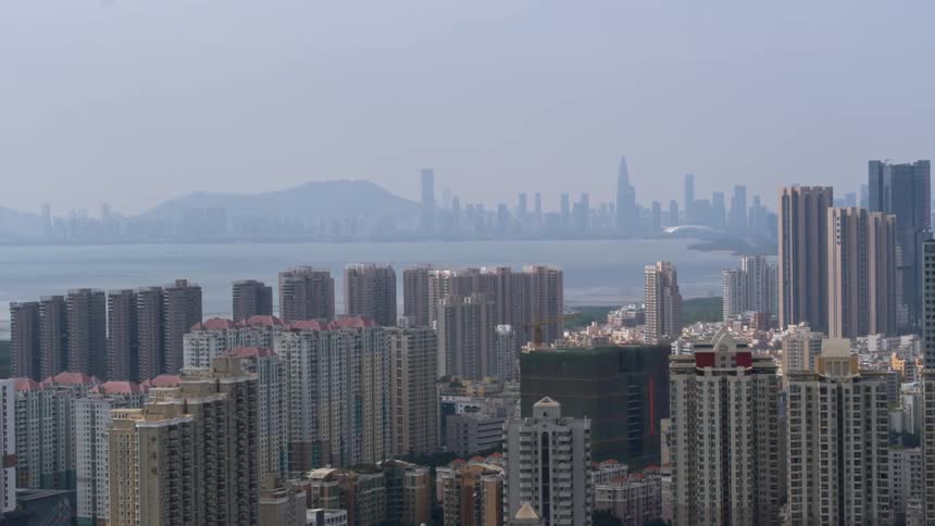 The tall buildings line the coastline on a foggy day