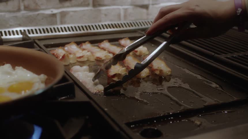 Bacon and eggs are cooked on a stovetop