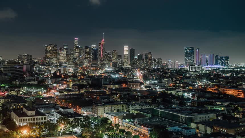 Thick clouds flowing over large city during the day then dissipating at night
