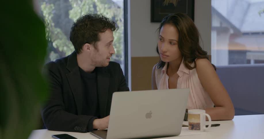 Two coworkers look at a laptop
