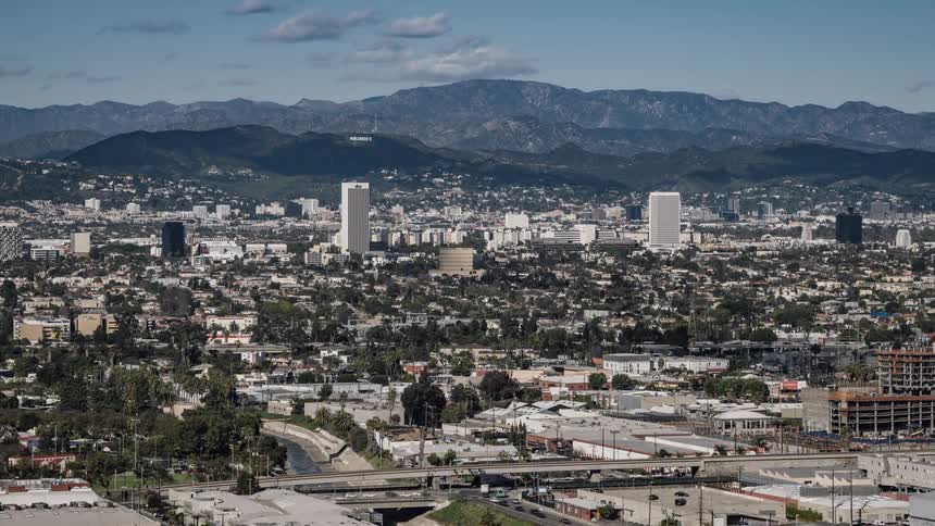 The vehicles move around the city near the mountains