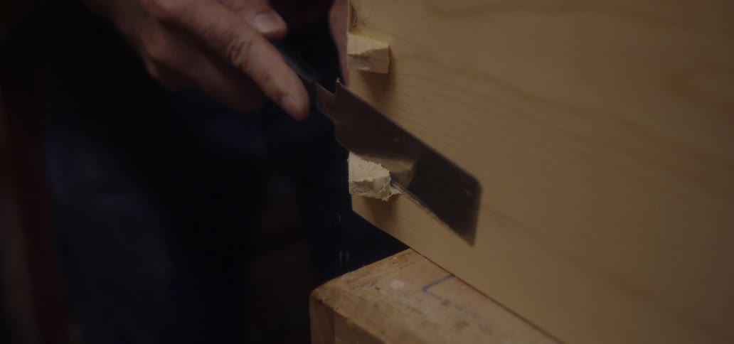 A man carves wood with a small knife