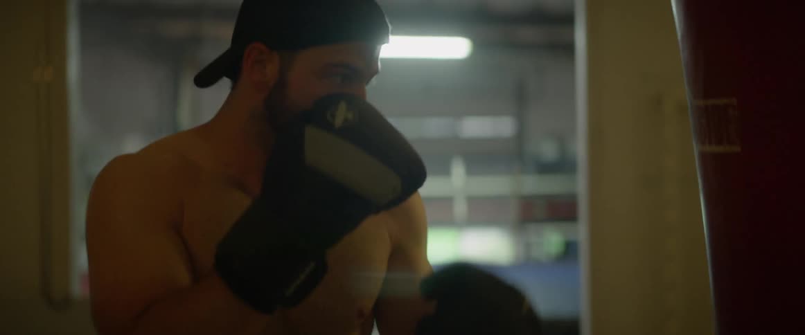 A man is punching the heavy bag in the gym