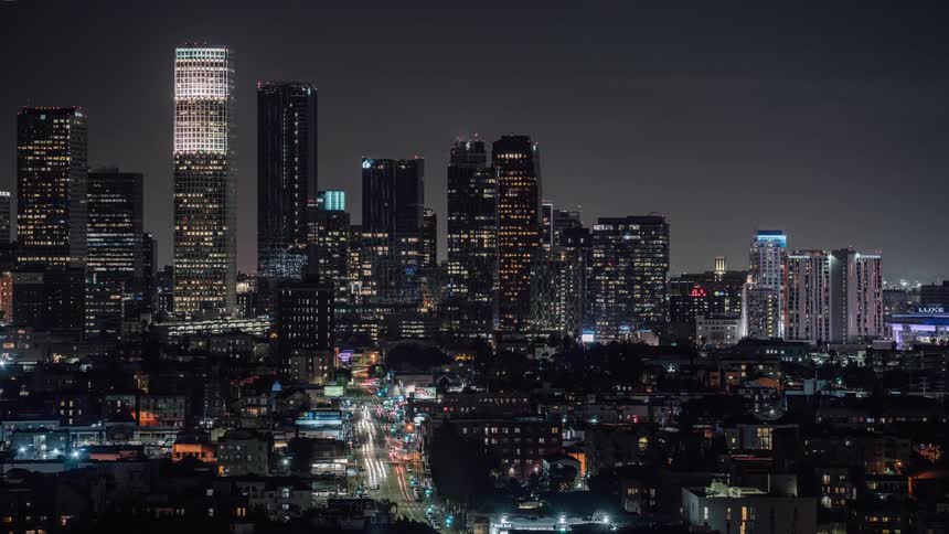 A city skyline at night with lights from windows and signs and traffic