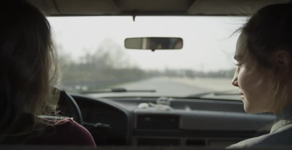 Two girls stare at each other while driving then look forward