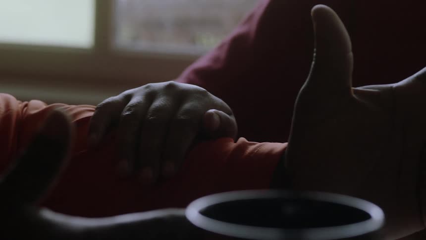A boy is clapping and listening to another boy as they sit at a table in daylight