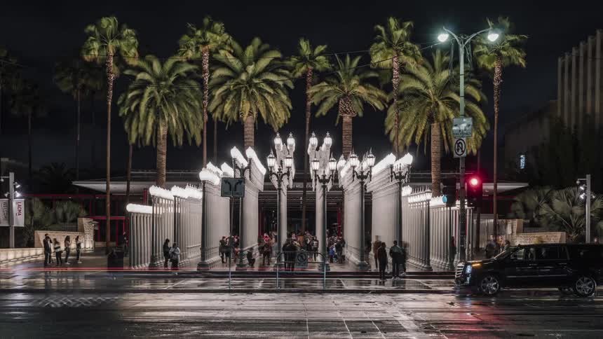 People walk on the plaza in front of a building on a rainy night
