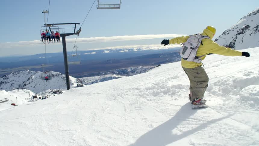 A man is snowboarding down a hill
