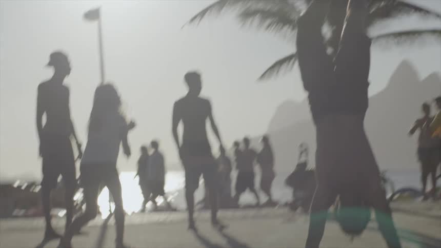 People are playing volleyball and doing flips by the beach