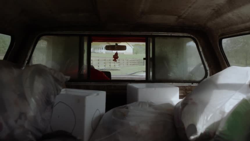 Boxes and bags in the back of a moving pickup with a cap